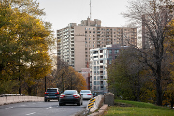 Urban road in Montreal's Cote des Neiges area during autumn, showcasing vehicles passing by with...