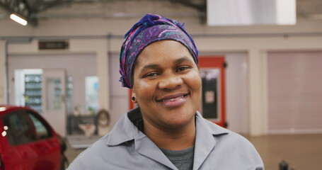 Portrait of an African American male car mechanic working in a township workshop, looking at the cam