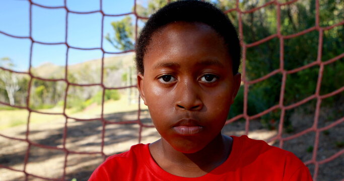 Determined boy standing against net during obstacle course in boot camp