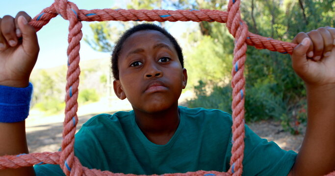 Tired boy leaning on net during obstacle course in boot camp