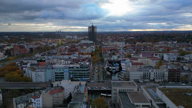 Cityscape of berlin featuring schlossstrasse in Steglitz, a construction crane, buildings, trees, and a cloudy sky. Great aerial view flight descending drone