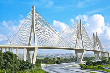 Fototapeta premium A modern cable-stayed bridge with a scenic backdrop and clear blue sky.
