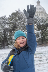 Portrait of kid in winter Washington DC. Child in knitted hat playing in a snowy winter park near Capitol. Child playing with sleigh ride. Winter kid play in snowy city park. Winter vacation with