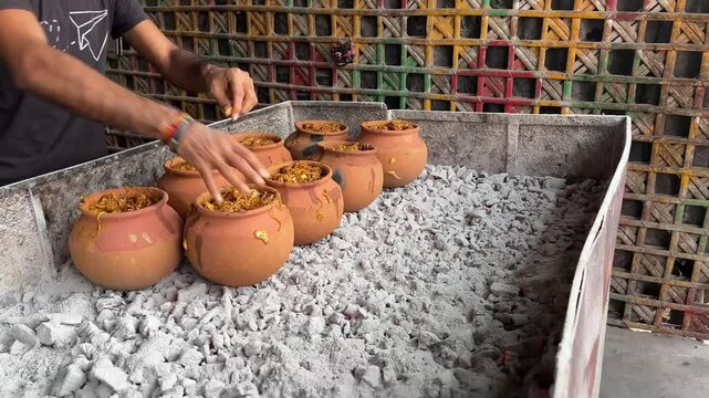A boy keeping earthen pot on stove for preparing Bihari style Champaran mutton