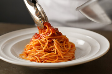 レストランのトマトソースのパスタを盛り付けるシェフ