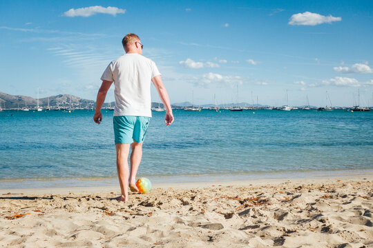 un homme joue au football sur la plage. Vacances &agrave; la mer. Foot sur une plage de sable. Touriste jouant au ballon au bord de la mer. Plage de Majorque. Vacancier aux Bal&eacute;ares
