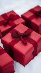 Obraz premium Four red gift boxes with burgundy ribbon bows on white surface.