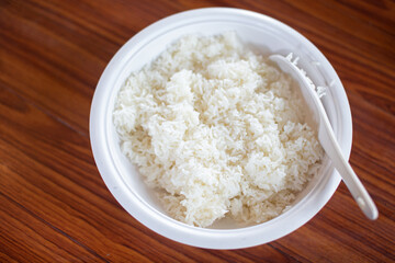 Cooked rice in white plate on wooden table with copy space