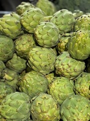 Fototapeta premium A pile of many fresh, green artichokes showcased in a market setting, highlighting their texture and natural vibrancy. Perfect for themes of organic produce and healthy living.