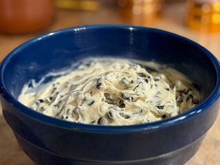 A blue bowl full of a sweet dessert, chocolate chip cookie dough dip. Perfect for dipping treats, pretzels, or cookies. A great party food.