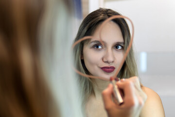 Caucasian women with blonde hair draws heart shaped use lipstick on the mirror and look at herself feeling confident self love