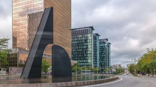 Timelapse of a fountain in a roundabout near Brussels North Station. Traffic flows around the intersection of Boulevards Simon Bolivar and Roi Albert II surrounded by modern glass skyscrapers. Belgium