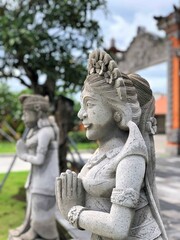 Traditional Balinese Stone Sculpture of a Woman in Prayer Posing Outdoors