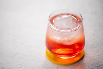 Closeup of a hand pouring sparkling water into a glass with red liquid and ice.