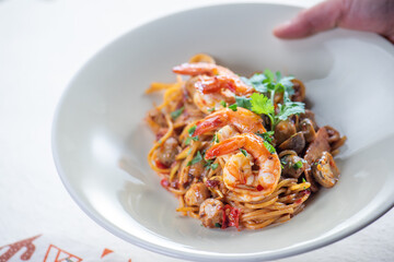 A plate of shrimp pasta with a fork and knife on a white tablecloth.