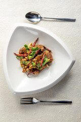 Close-up of a plate of stir-fried meat with red chilies and herbs.