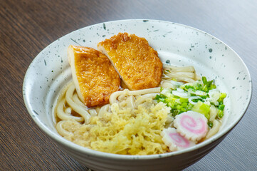 A bowl of udon noodles with a large tempura prawn.