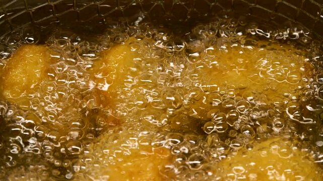 Closeup slow motion crispy fried chicken meat nuggets deep frying in boiling oil