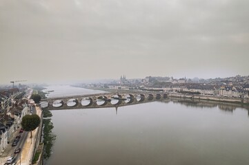 Fototapeta premium Beautiful twilight over the serene Loire River with a historic bridge in a misty French town