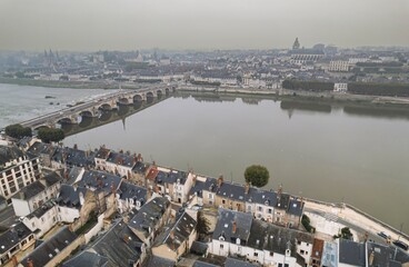 Fototapeta premium Historic town along the riverbank featuring picturesque architecture and a serene bridge on a misty day