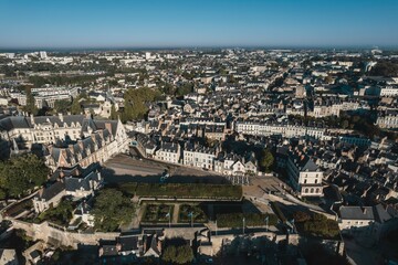 Panoramic view of a charming historical town nestled amidst rolling hills under a clear blue sky