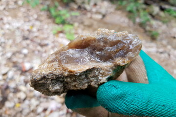 Wet sample of chalcedony in hand, search for stone-cutting raw materials in nature