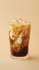 A glass of iced coffee with milk swirling inside, against a warm beige background