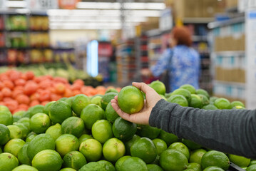 Female hand holding a lemon in a supermarket.