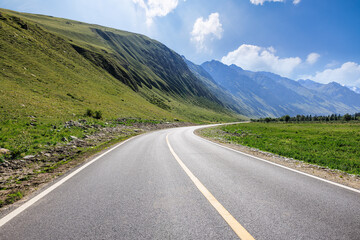 Countryside asphalt road and green grassland with mountain natural landscape in Xinjiang, China. Outdoor road background.