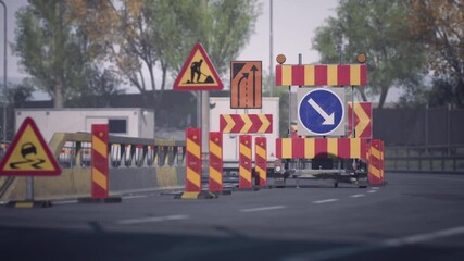 Road construction is in progress with various traffic barriers and informative signs directing vehicles. The area is lined with trees, creating a suburban atmosphere during daytime.