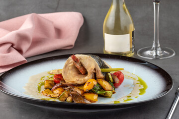 Shrimp wrapped in sea bass on various vegetables on a porcelain plate