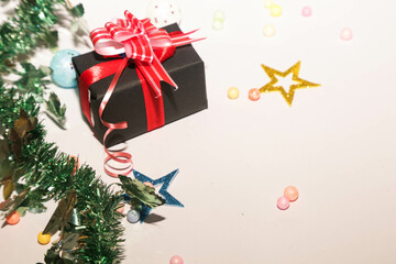 Season's greetings scene. Christmas decorations,gift boxes with red ribbons, сhristmas balls,  rustic star, holly berries, frosty spruce branches, confetti on white backdrop, selective focus with blur