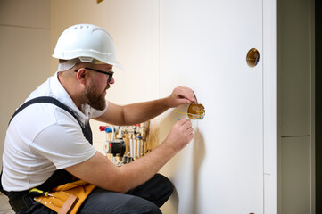 Builder installing electric socket in new apartment. Installing electrical wall outlets with a...