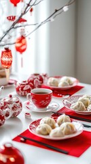 Chinese New Year dining table setting with dumplings, tea, and festive red decorations.