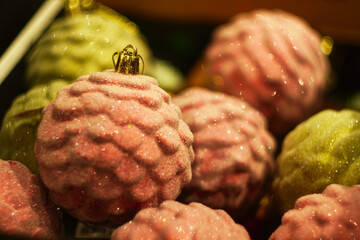 Close-up of textured pink and green Christmas ornaments with glittering details, creating a festive...