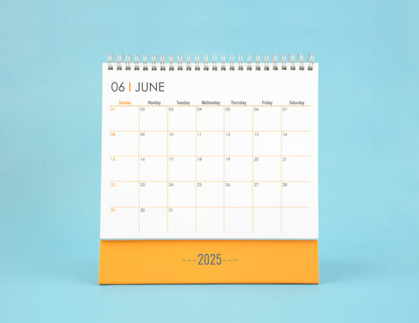 June 2025 white desk calendar on blue color background.