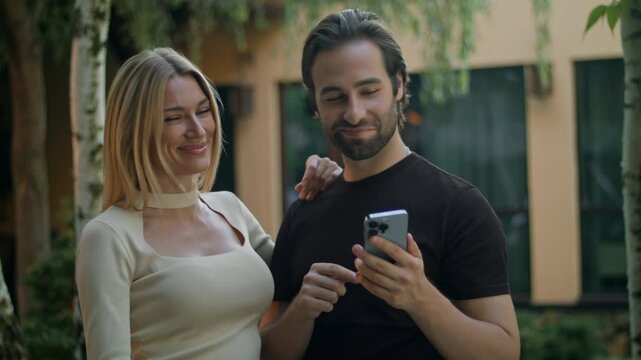 The couple watch the phone, using a mobile app to win a prize on an smartphone. With a green screen displayed, the couple is delighted, celebrating their good fortune and enjoying the sudden success.