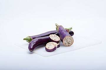 Fresh purple eggplant cut into pieces and whole photographed against a white background
