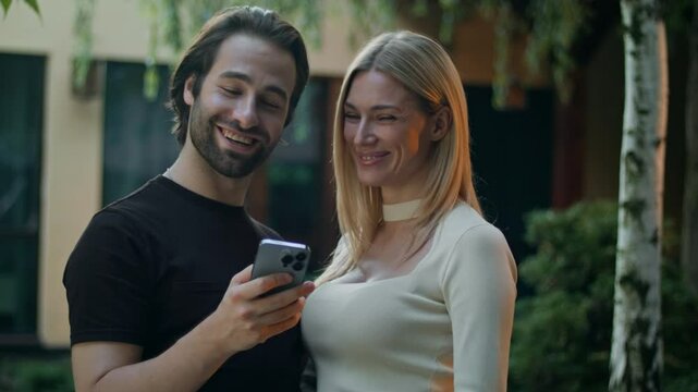 A guy and girl with a phone look at the screen. They can't believe they won a prize so easily in a mobile app. Surprised, they don't show the phone to the camera. They are very pleased with their win.