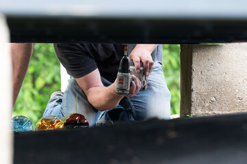 Installation work of a wooden gazebo, the master is screwing screws into the wooden floor.