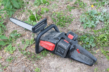Naklejka premium Electric saw for woodworking. Cordless saw lies on the grass.