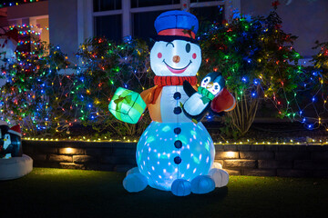 Luminous inflatable figure of Snowman decorating front yard at night