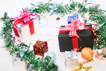 Season's greetings scene. Christmas decorations,gift boxes with red ribbons, сhristmas balls,  rustic star, holly berries, frosty spruce branches, confetti on white backdrop, selective focus with blur