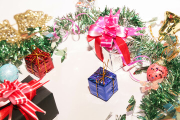 Season's greetings scene. Christmas decorations,gift boxes with red ribbons, сhristmas balls,  rustic star, holly berries, frosty spruce branches, confetti on white backdrop, selective focus with blur