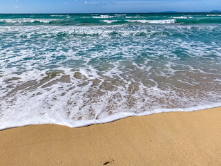  coastal scene with turquoise waves touching sandy beach, distant horizon. High quality photo