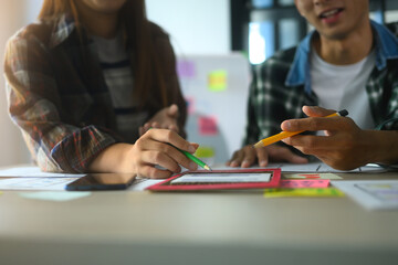 Close up of designers collaborating on a UX UI project, using colorful sticky notes and wireframes