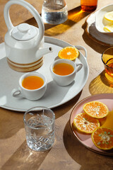 Two cups of hot orange juice served on a white plate accompanied with orange slices.