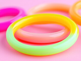 Colorful, translucent plastic rings stacked on a pink background 