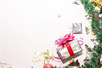 Season's greetings scene. Christmas decorations,gift boxes with red ribbons, сhristmas balls,  rustic star, holly berries, frosty spruce branches, confetti on white backdrop, selective focus with blur