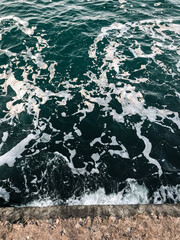Sea water surface - waves on the sea. Splashes and texture on dark teal green water.
